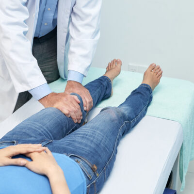 Cropped image of chiropractor checking knee of young patient